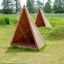 Tipi Nature wooden house fa játszótéri sátor zöld fűvel körülvéve.