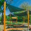 Outdoor Classroom fa padokkal, napernyőkkel, táblával és virágcserepekkel szabadtéri tanulóhely.