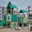 Tower playhouse with a slide zöld játszótéri mászókával és csúszdával, gyerekek játszanak körülötte.