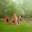 Wigwam wooden house három fa játszóház zöld füves területen, ablakokkal és nyílásokkal.